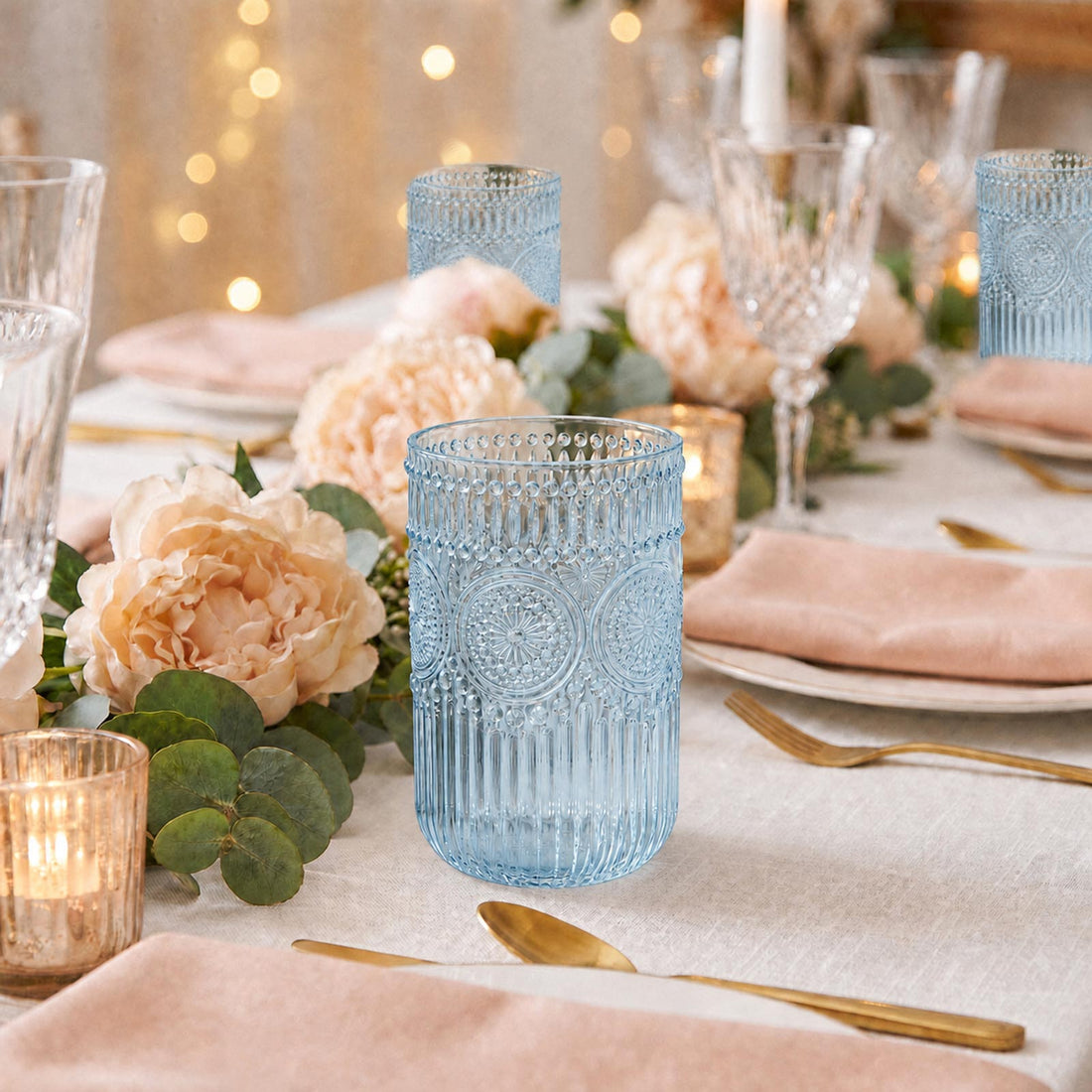 Elegant blush and gold wedding table setting with blue textured glassware