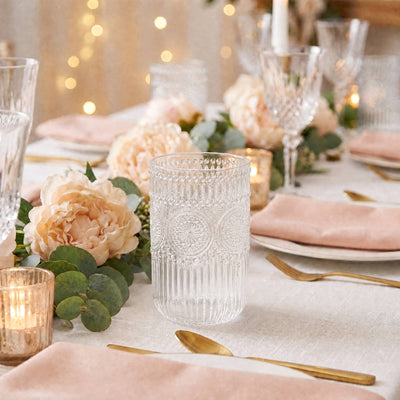 Elegant blush and gold wedding table setting with floral centerpiece and crystal glassware