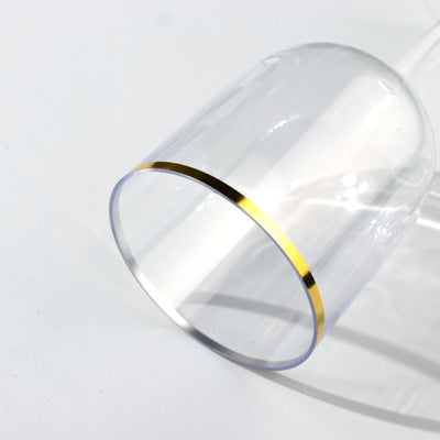 Clear glass with a gold rim, angled on a plain background.