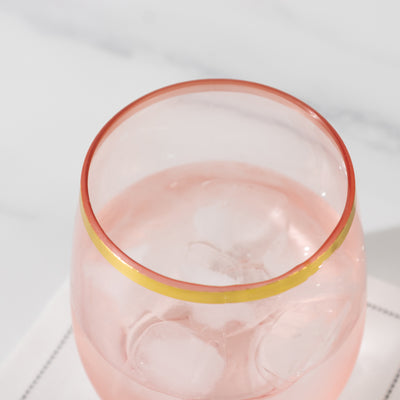 Pink glass with ice and a yellow rim on a light surface.