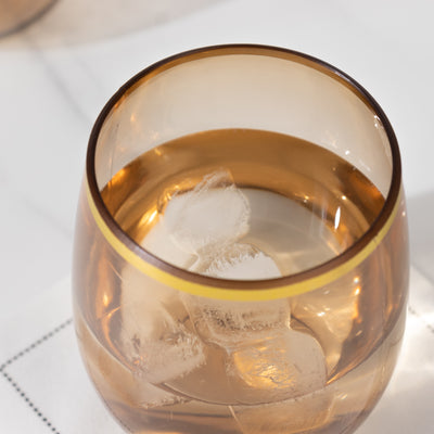 Amber glass with ice cubes, reflecting light in a stylish setting.