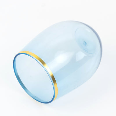 Blue glass tumbler with gold rim, angled view.