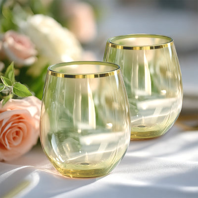 Elegant gold-rimmed stemless wine glasses with a soft green tint.