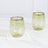 Set of two elegant green glasses with gold rims on a marble surface.