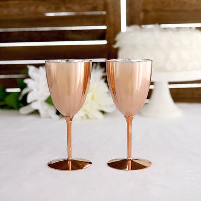 Rose gold champagne flutes on a table with a floral backdrop.