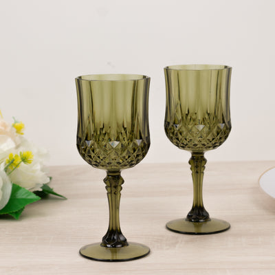 Green crystal wine glasses set on a table with floral decor.