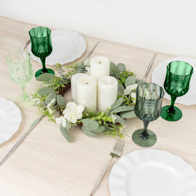 Elegant green glassware and candles on a table centerpiece with floral accents.