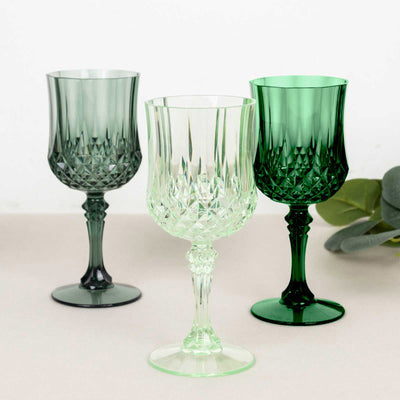 Three elegant crystal wine glasses in green and clear shades.