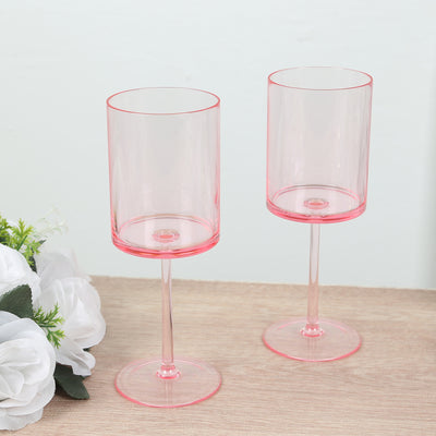 Set of two pink plastic wine glasses on a wooden surface.