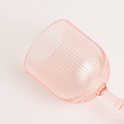 Pink ribbed glass wine goblet on a white background