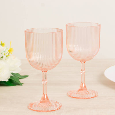 Set of two ribbed pink glass goblets on a table.