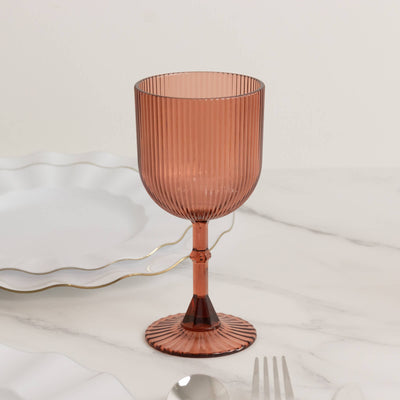 Rose-colored ribbed glass goblet on a marble table.