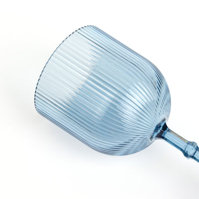 Blue ribbed glass wine goblet on a plain backdrop.