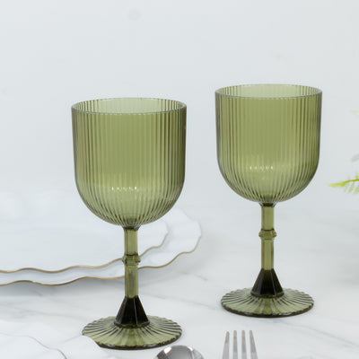 Green ribbed glass goblets on a plain backdrop.