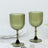 Green ribbed glass goblets on a plain backdrop.
