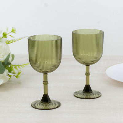 Green ribbed glassware set on a wooden table with floral accents.