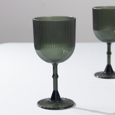 Green ribbed glass goblet on a plain backdrop.