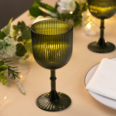 Green ribbed glass goblet on a table with floral decor and soft lighting.