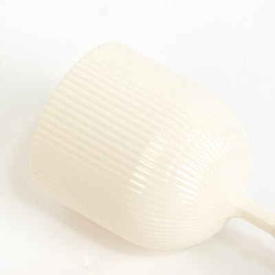 White ribbed ceramic mug on a plain backdrop.