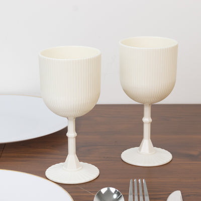Set of two elegant ribbed cream-colored goblets on a wooden table.