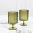 Green ribbed glass goblets on a marble table setting.