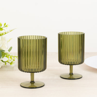 Set of two green ribbed glass dessert cups on a wooden table.