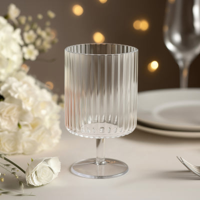 Elegant ribbed glassware on a dining table with floral accents and soft bokeh lights.