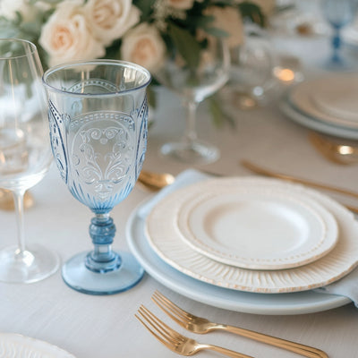 Elegant blue glass goblet on a beautifully set dining table with plates and cutlery.