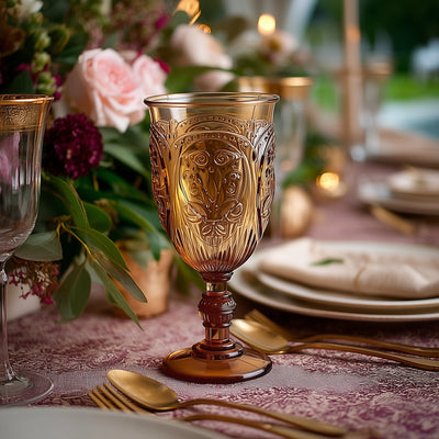 Elegant amber glass goblet on a beautifully set dining table adorned with flowers.