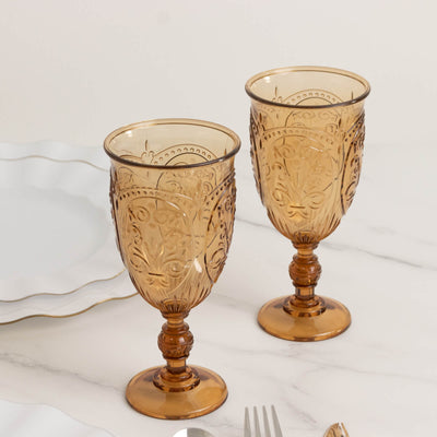 Amber glass goblets with intricate floral patterns, set against a marble surface.