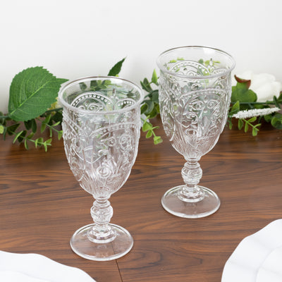 Vintage embossed glass goblets on a wooden table with greenery.