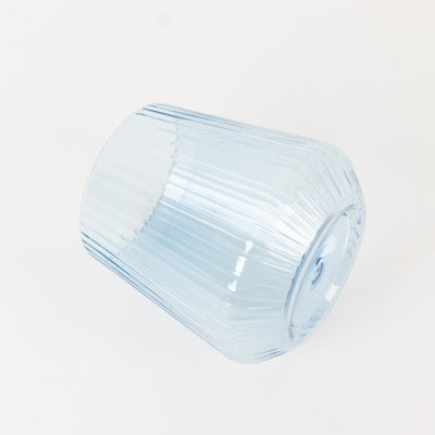 Blue ribbed glass tumbler on a plain background