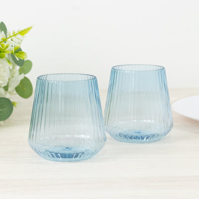 Blue ribbed glass tumblers on a light wooden surface.