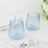 Set of two ribbed blue glass tumblers on marble surface.