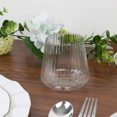 Clear ribbed glass tumbler on a wooden table with floral decor.