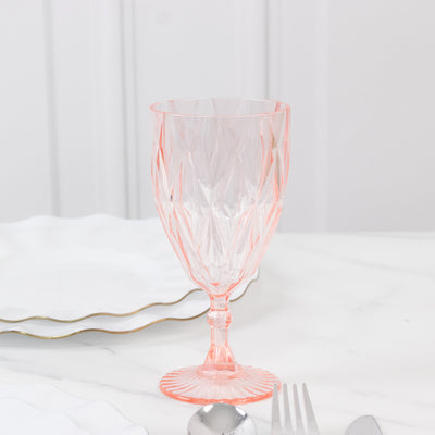 Pink crystal glassware on a dining table with silverware.