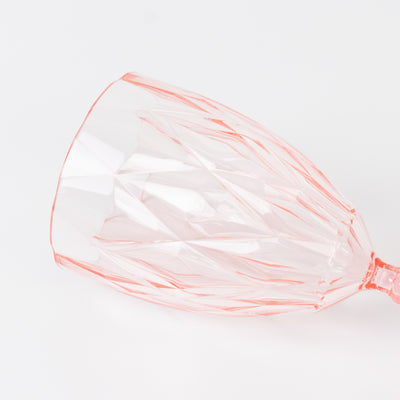 Pink crystal wine glass with geometric design on a white background.