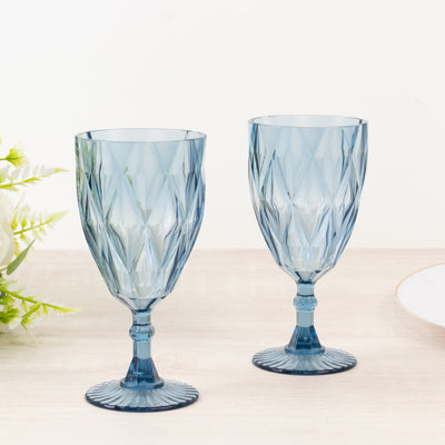 Blue crystal goblets set on a light wooden surface.