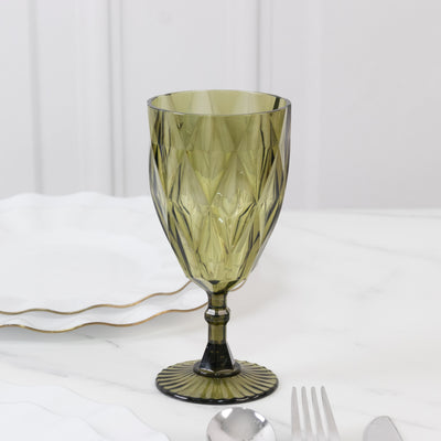 Green diamond-cut glass goblet on a marble table with white plates.