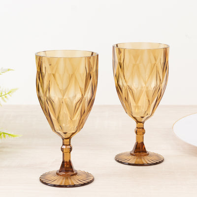 Amber crystal goblet glasses set on a wooden table.