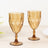 Amber crystal goblet glasses set on a wooden table.