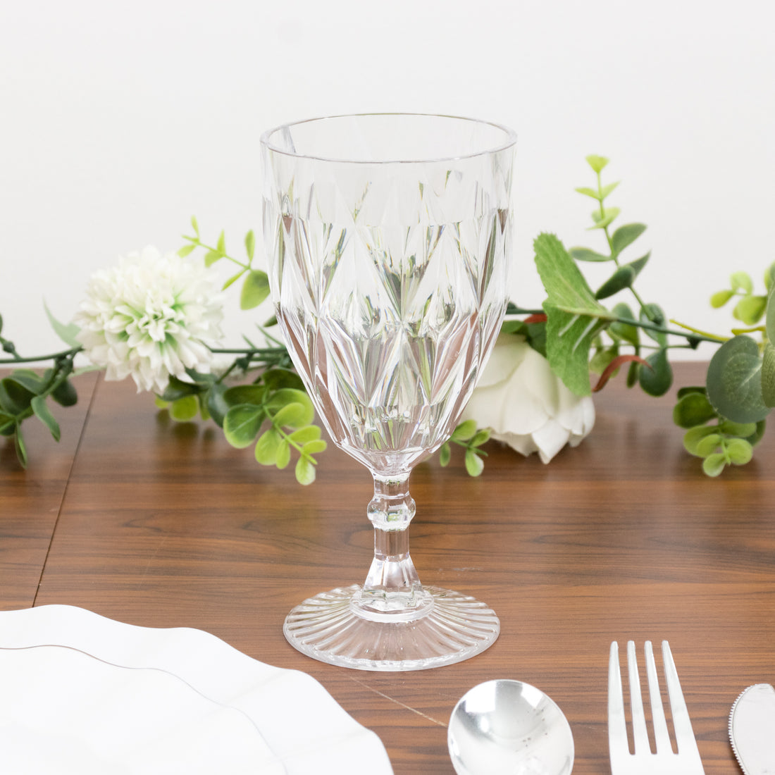 Crystal wine glass with intricate cut design on a wooden table setting.