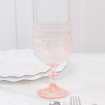Pink vintage glass goblet with intricate design on a marble table.