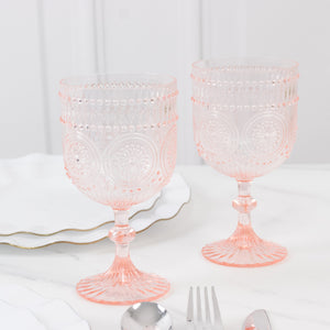Set of two vintage-inspired pink glass goblets on a marble table.