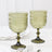 Green decorative goblets on a marble table setting.