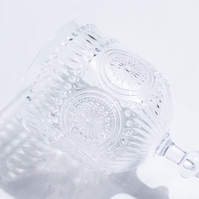 Clear decorative glass cup with intricate patterns and a stem.