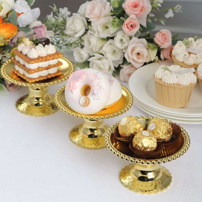 Elegant gold dessert stands with assorted pastries and flowers in the background.