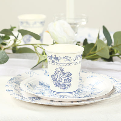 Blue floral disposable cup and plates on a table with greenery.