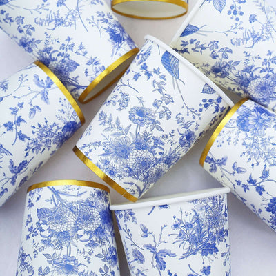Decorative blue floral paper cups with gold rims arranged in a stylish composition.