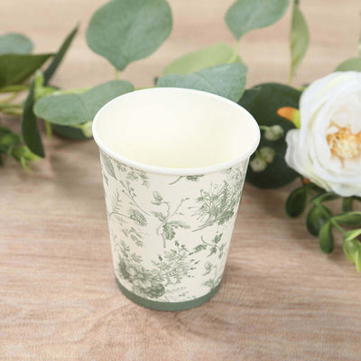Floral-patterned paper cup surrounded by greenery.